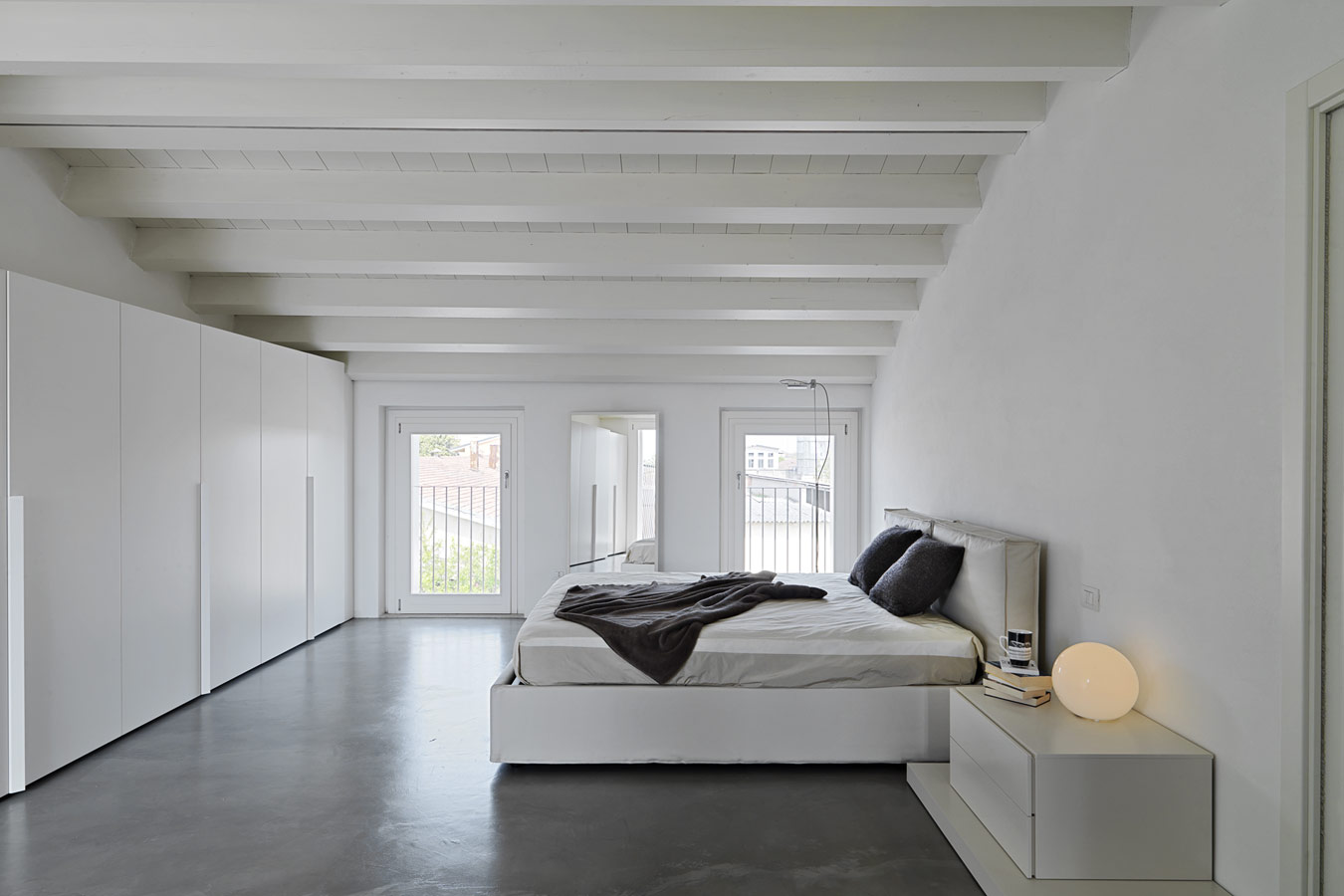 Moderne slaapkamer met betonnen vloer en inbouwkasten